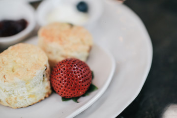 Butter scones served with jam and clotted cream with strawberries on white plate.Breakfast, Traditional English Afternoon Tea, Scones with Clotted Cream and Strawberry Jam, Selective Focus