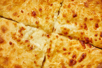 Close up view on tasty traditional Khachapuri - closed baked pie stuffed with melted salt cheese (suluguni) or meat on wooden tray. Traditional georgian food