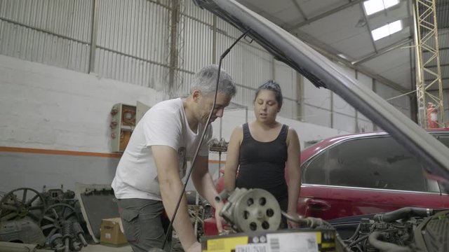 Mechanic couple repairing car engine