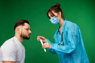 Female doctor examining her male patient. Isolated on green background. Doctor with stick to make swab test.