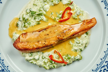 Fototapeta na wymiar Delicious grilled salmon steak filet with peas in a creamy sauce in a white plate on a wooden background. Tasty seafood