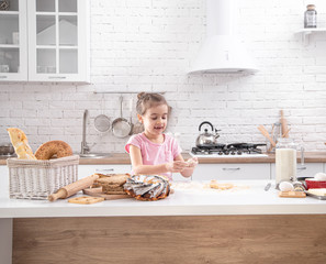A cute little girl is cooking homemade cakes in the kitchen.