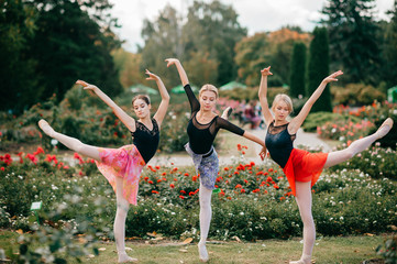 Three flexible ballet dancers balancing and posing at nature