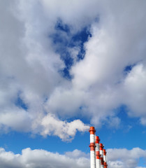 the pipes of the heat station are red and white smoke into the sky