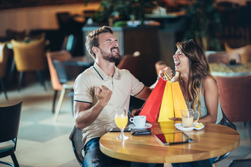 Young couple enjoying in modern cafe after shopping.