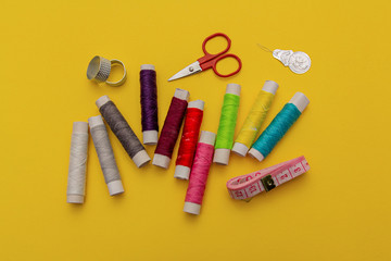 Thread, needles, scissors and meter on yellow background. tailoring set. sewing kit multi-colored.