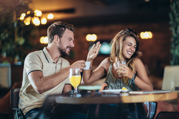 Beautiful young couple using a smartphone and smiling while sitting in the cafe