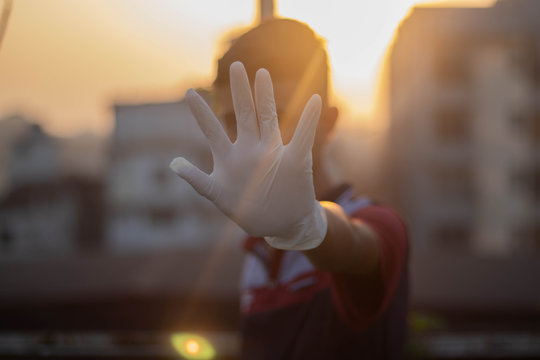 Stop The Virus! Conceptual Photo About Fever, Pneumonia, Novel Coronavirus In China. Blurred Quarantine Officer Wearing A Protective Suit, Breathing Mask And Medical Gloves Makes A Stop Hand Gesture