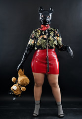 woman with rubber mask for protection posing with her teddy bear on black background alone