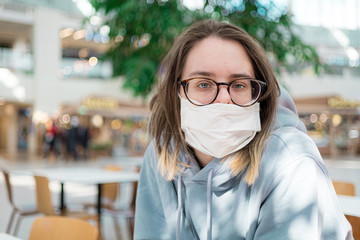 Woman in medical face mask siting in mall close up portrait. Corona virus infection protection