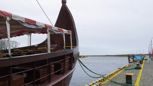 replica of viking ship sway slowly berthed in Kolobrzeg, Poland; view from a front