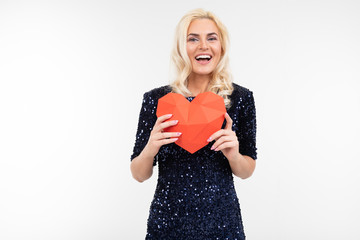 blond young woman in blue dress holding a paper red heart on a white background with copy space