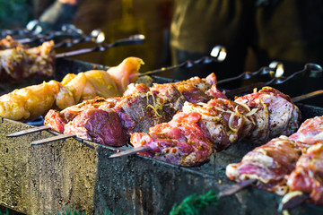 Grilling pork and chicken meat on skewers outside