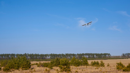 Flight of a radio-controlled airplane over a field.
