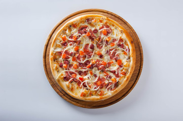 meat pizza lies on a wooden round board on a white background