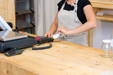 Detail of female hands printing a receipt from a POS terminal.