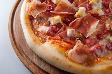 meat pizza lies on a wooden round board on a white background, close-up