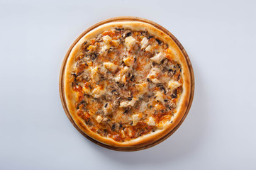 meat pizza lies on a wooden round board on a white background