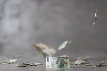 Polskie pieniądze na biurku, w tle spadające nominały 100 złotych, polska waluta