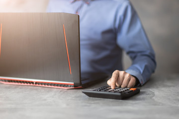 Bizmesmen przy laptopie liczączy na kalkulatorze.