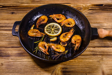 Roasted shrimps with lemon slice, garlic and rosemary in a cast iron pan