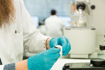 Fototapeta na wymiar Closeup of man's hand in gloves preparing machine to perform analysis of sample suspected for coronavirus infection. Covid-19 pandemics laboratory diagnosis.