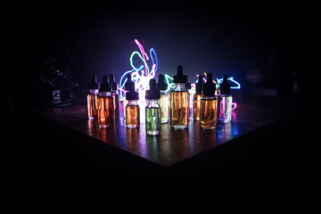 Smoke clouds and vape liquid bottles on dark background. Light effects. Useful as background or...