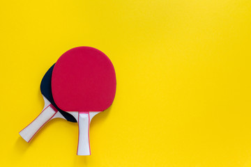 Red and black tennis ping pong rackets isolated on a yellow background, sport equipment for table tennis