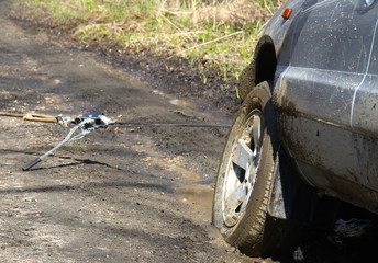 a grey SUV is towed by a hand winch out of the mud on a forest road