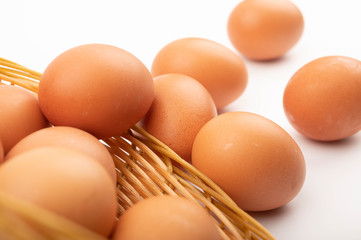 Chicken eggs in a wicker basket and scattered eggs on a white background. Close up.