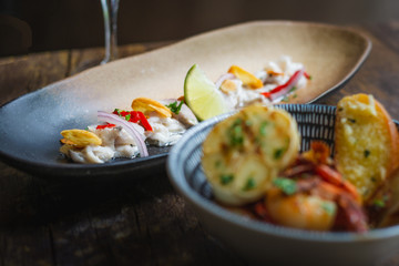 Lubina Ceviche with lime juice, shallots, a wedge of lime and fried garlic