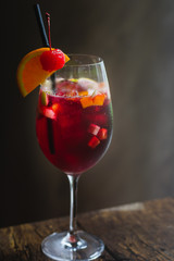 a glass of sangria in a tall glass with a wedge of orange and cherry