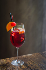 a glass of sangria in a tall glass with a wedge of orange and cherry