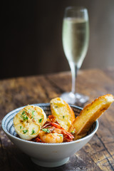 Prawns Al Ajillo with garlic, fried garlic, chilli oil and garlic bread in a bowl