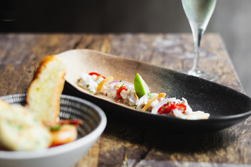 Lubina Ceviche with lime juice, shallots, a wedge of lime and fried garlic