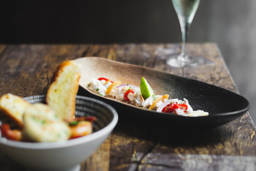 Lubina Ceviche with lime juice, shallots, a wedge of lime and fried garlic