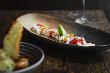 Lubina Ceviche with lime juice, shallots, a wedge of lime and fried garlic