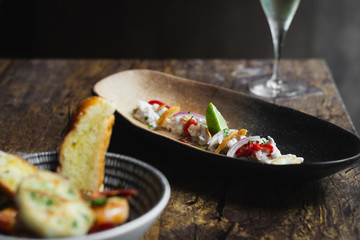 Lubina Ceviche with lime juice, shallots, a wedge of lime and fried garlic