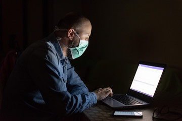 Man wearing mask and working from home in isolation from coronavirus