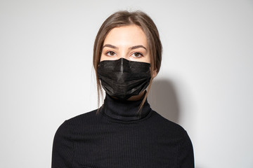 a girl in black clothes putting a black medicinal mask 