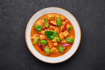 Thai Panang Chicken Curry in white plate at black slate background. Phanaeng Curry is thai cuisine dish with chicken, kaffir lime leaves, red curry sauce and vegetables. Thai food. Thailand meal