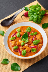 Thai Panang Chicken Curry in white plate at black slate background. Phanaeng Curry is thai cuisine dish with chicken, kaffir lime leaves, red curry sauce and vegetables. Thai food. Thailand meal