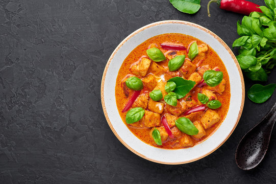 Thai Panang Chicken Curry in white plate at black slate background. Phanaeng Curry is thai cuisine dish with chicken, kaffir lime leaves, red curry sauce and vegetables. Thai food. Copy space
