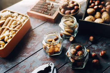Mix of nuts in boxes, bowls and glass jars on dark wooden table, walnuts, almond, hazelnut, cashew