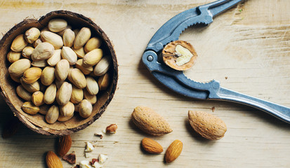 Mix of nuts in coconut bowls on dark wooden table, walnuts, almond, hazelnut, cashew, healthy various superfoods