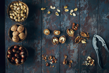 Mix of nuts in coconut bowls on dark wooden table, walnuts, hazelnut, cashew, healthy various superfoods