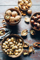 Mix of nuts in coconut bowls on dark wooden table, walnuts, almond, hazelnut, cashew, healthy various superfoods