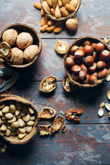 Mix of nuts in coconut bowls on dark wooden table, walnuts, almond, hazelnut, cashew, healthy various superfoods