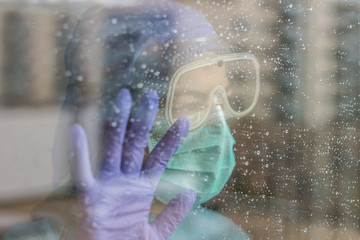 Fototapeta premium Photo of nurse inside hospital, with protective equipment for coronavirus, isolated due to quarantine. Rainy day.