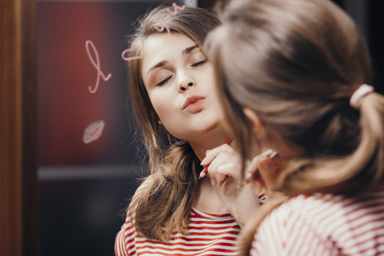 reflection of young woman face in mirror with inscription "I love you", painted heart and lip kiss ,romantic girl send air kiss, concept love and emotions